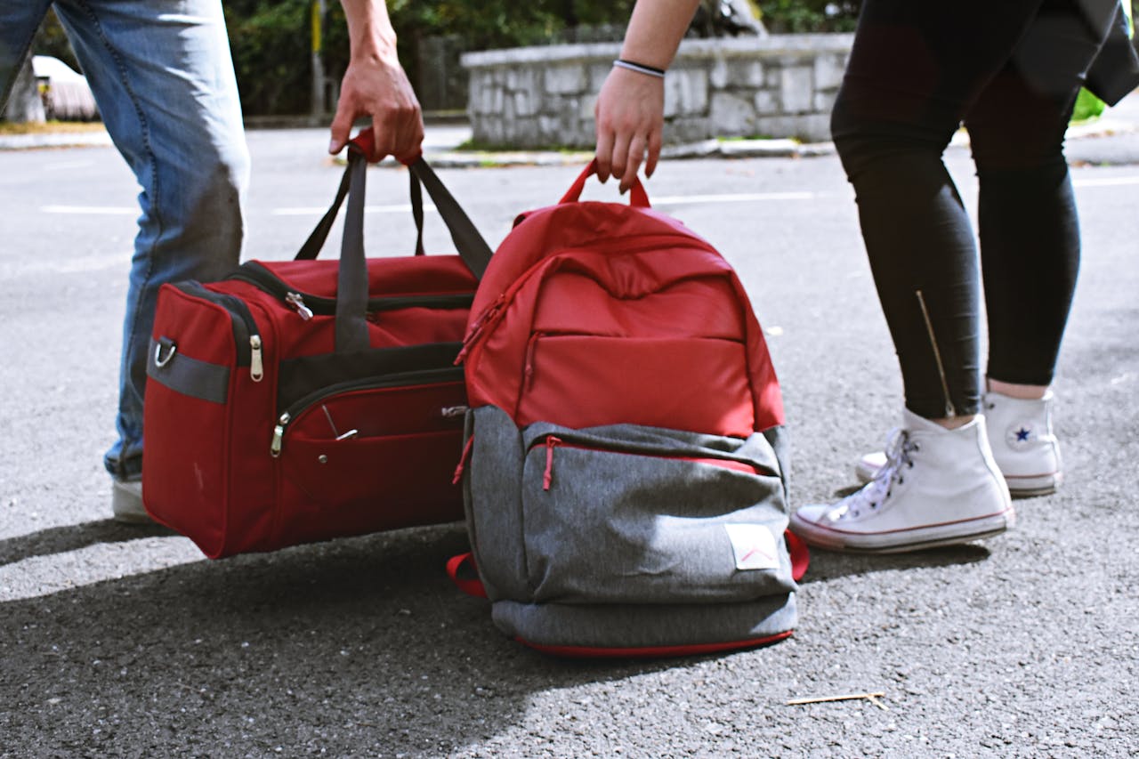 about-us Two travelers holding red bags on a street, symbolizing travel and exploration.